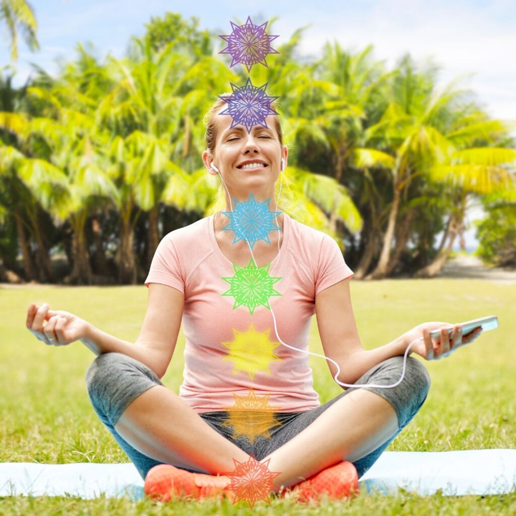 Happy woman meditating in a sunny park with seven chakra symbols