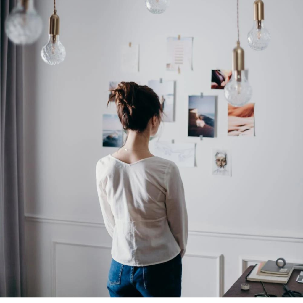 Woman Under Pendant Lights Looking at the Photo on the Wall