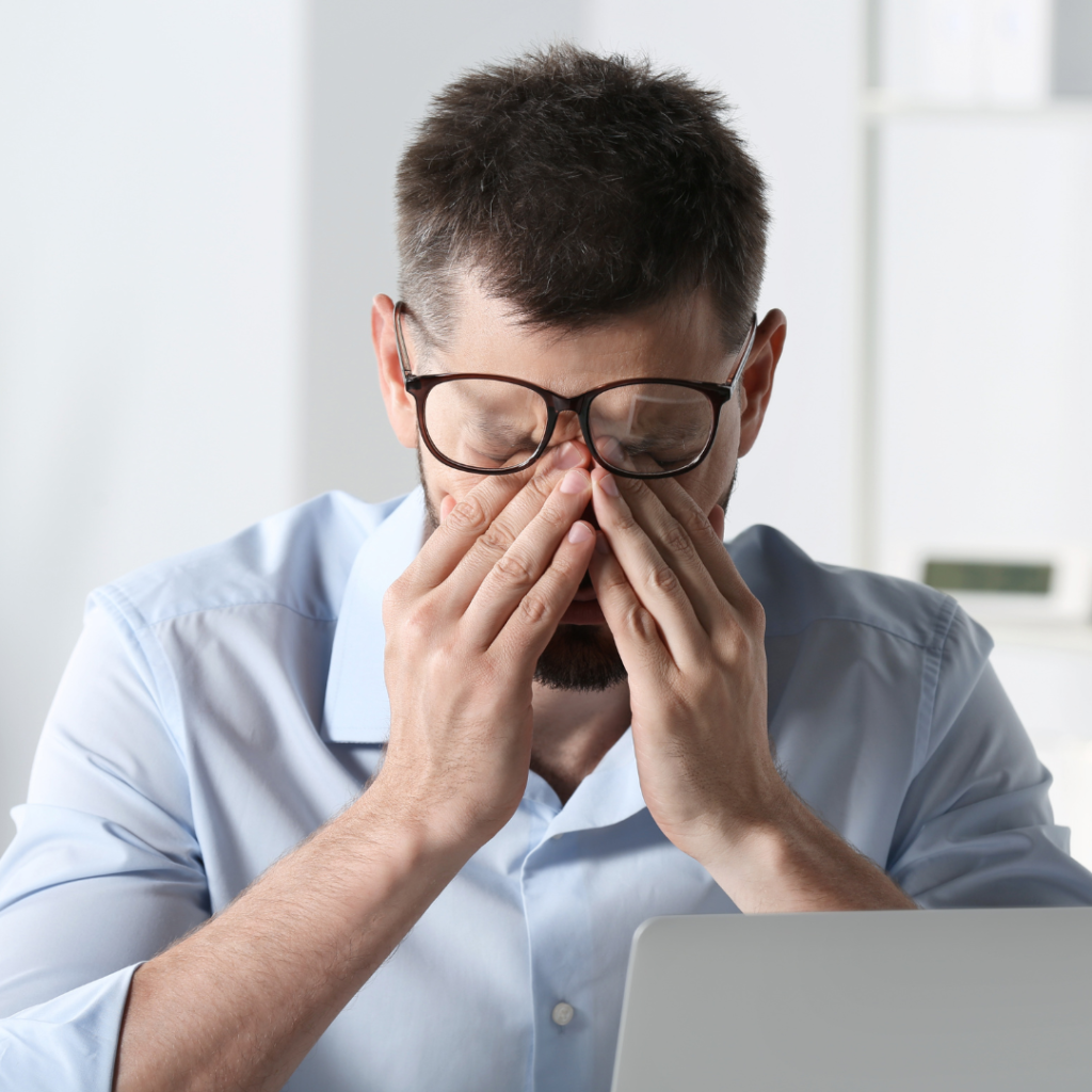 man suffering from eyestrain at workplace in office