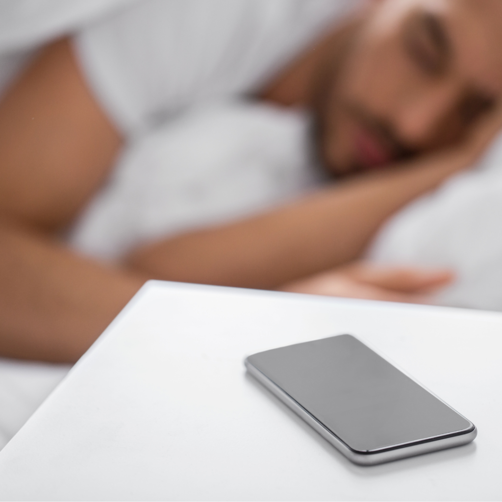 Smartphone on Bedside Table near Sleeping Man