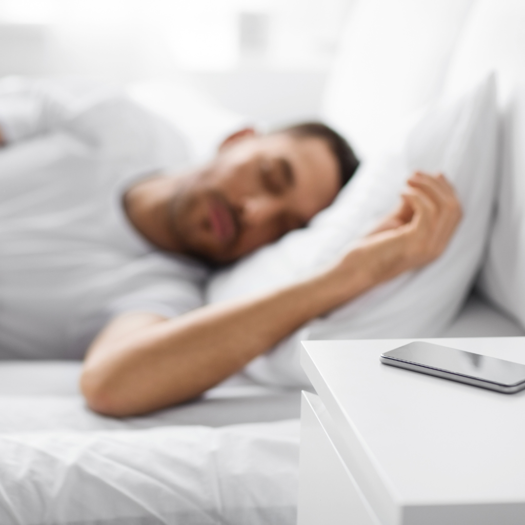 Smartphone on Bedside Table near Sleeping Man