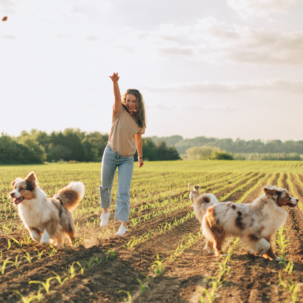 happy young woman playing with her dogs outdoors in the countrys