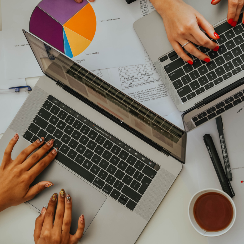 Persons Using Laptops on Table with Charts