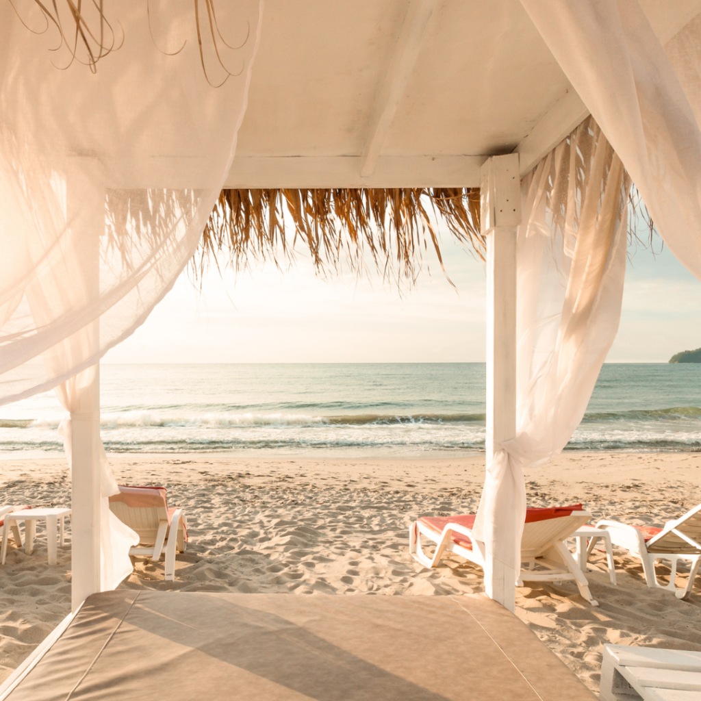 Canopy Bed with White Drapes on an Empty Beach