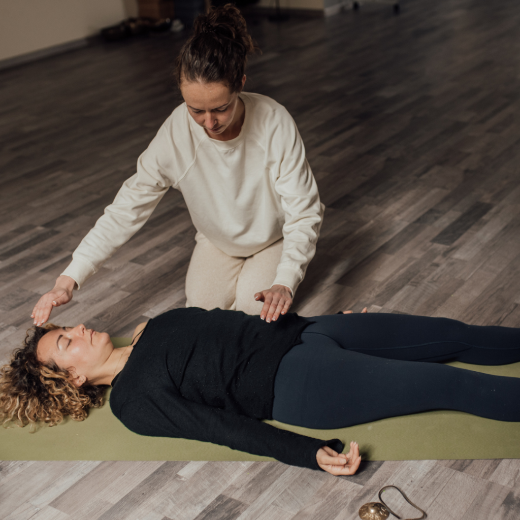 Energy practitioner healing relaxed woman on yoga mat
