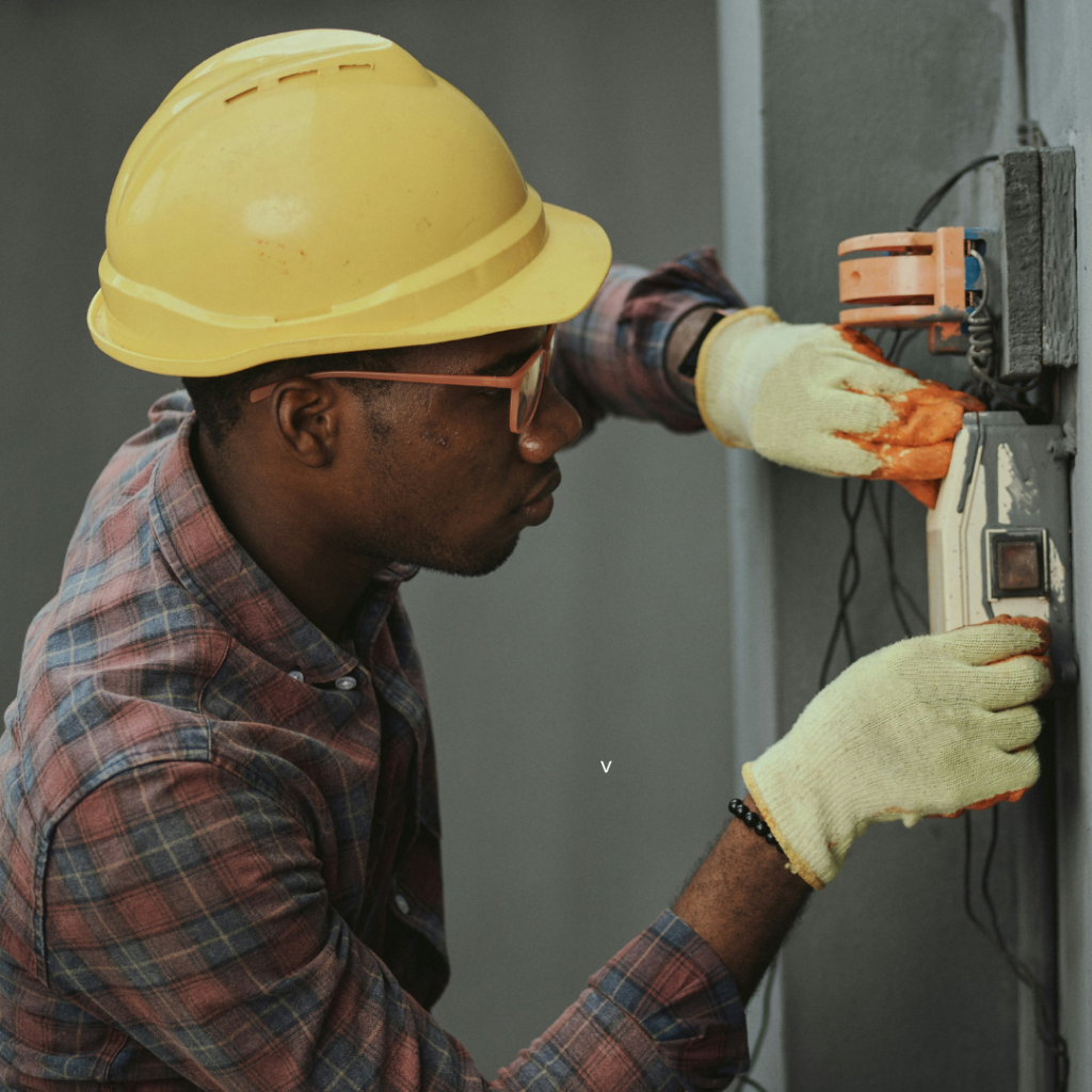 Portrait of a black man architect at a building site looking at camera. Confident civil engineering wearing a hardhat and eye goggles. Successful mature civil engineer at a construction site with open