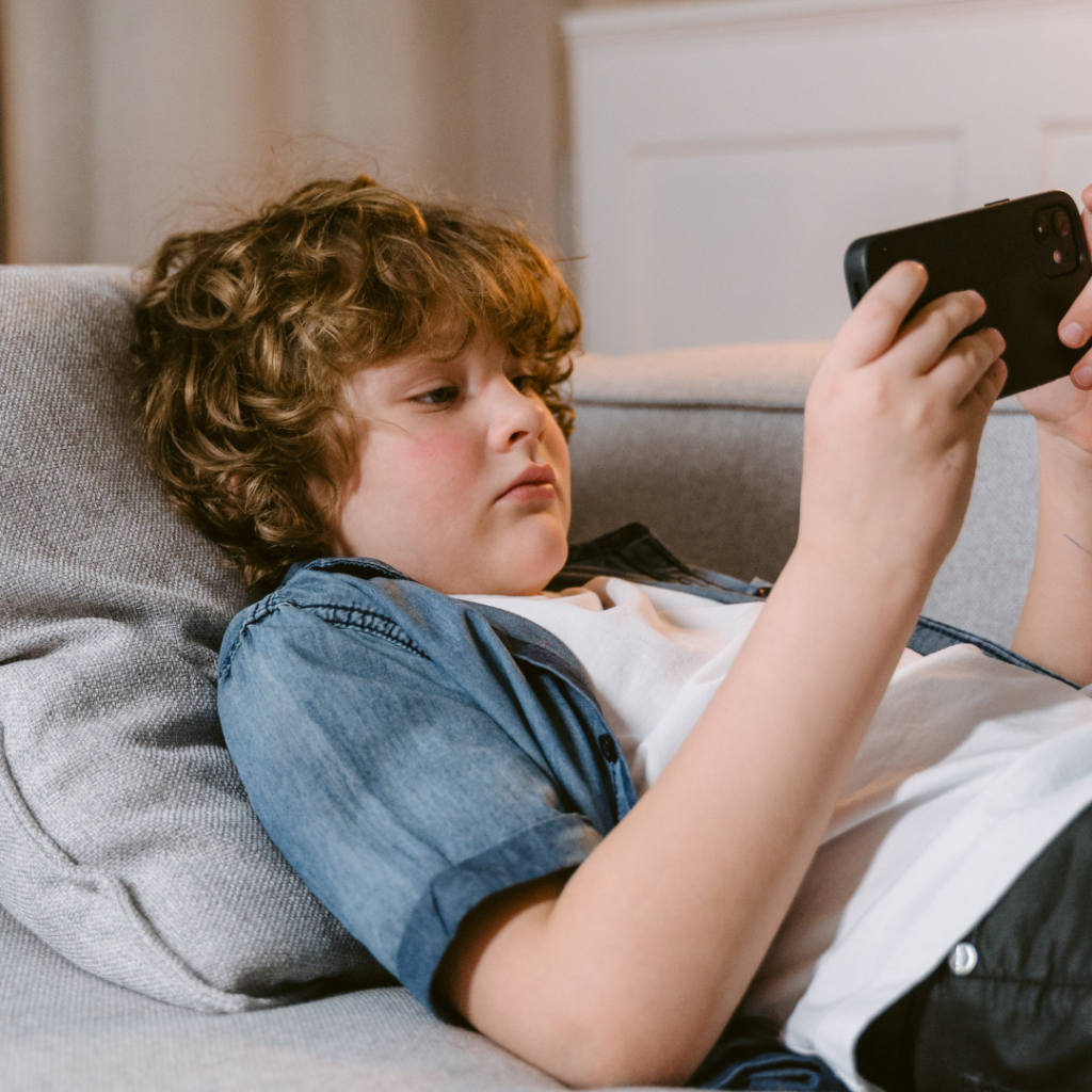 A Boy Using a Smartphone while Lying on a Sofa