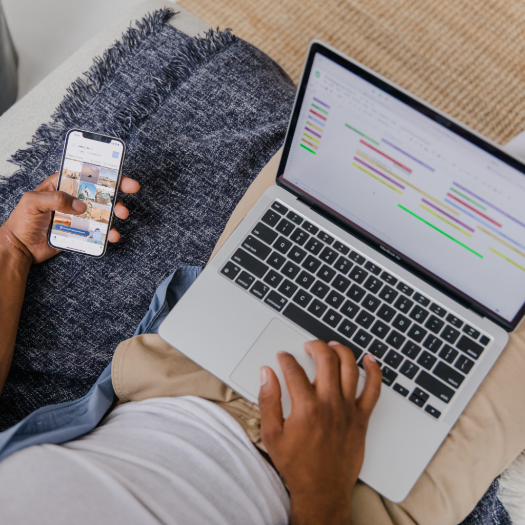 High Angle View of Man with Laptop on Lap and Phone in Hand