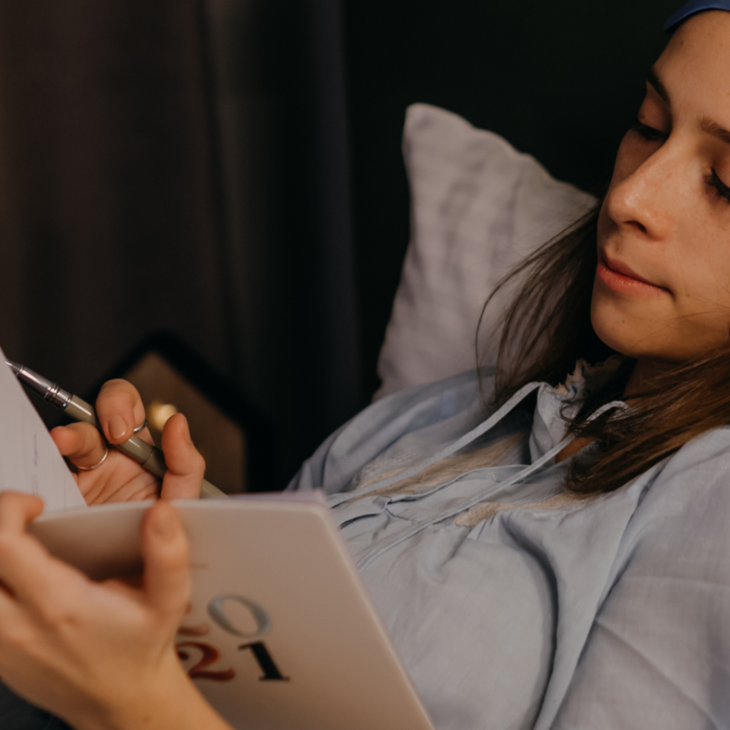 A Woman Writing on Her Journal while Lying in Bed