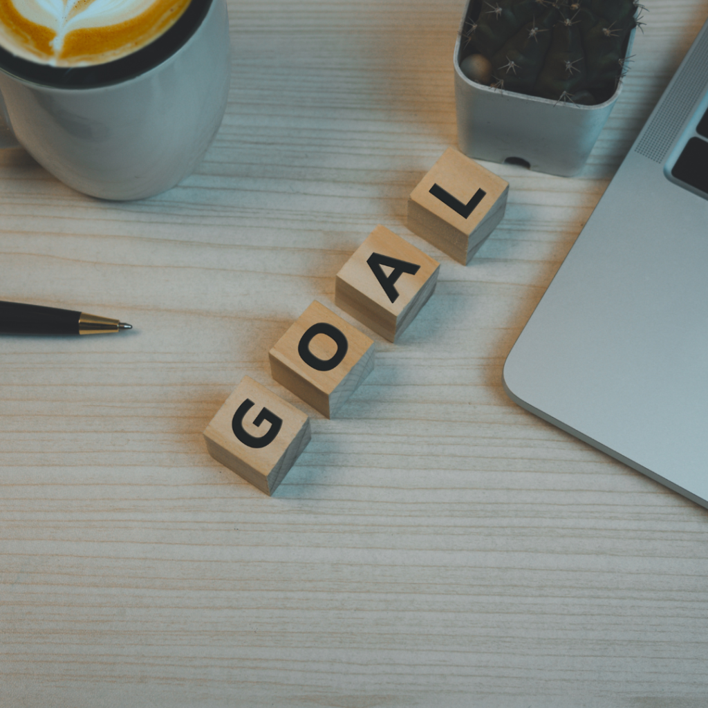 Wood cube block goal and pen coffee with computer laptop on table top view background. Copy space business idea plan success concept.