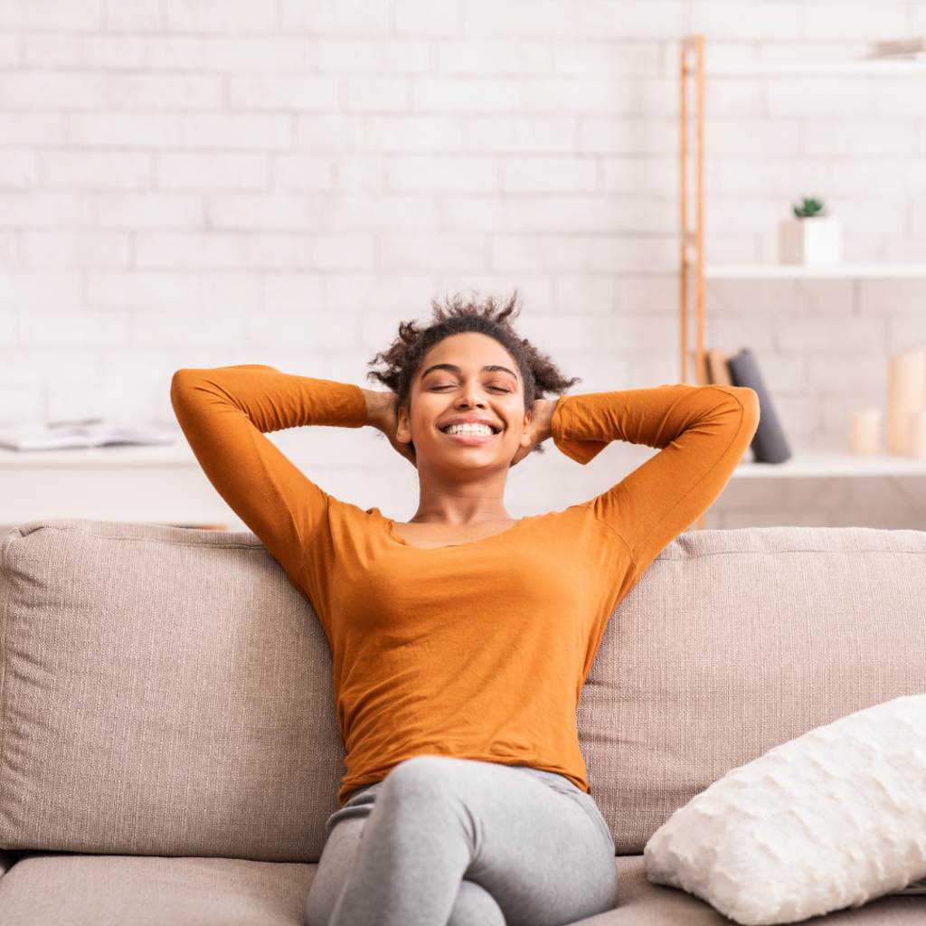 Happy Black Woman Relaxing Sitting On Sofa At Home