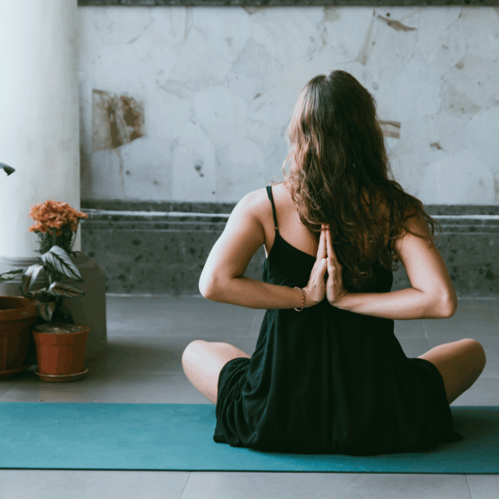 woman wearing black shirt sitting on green yoga mat