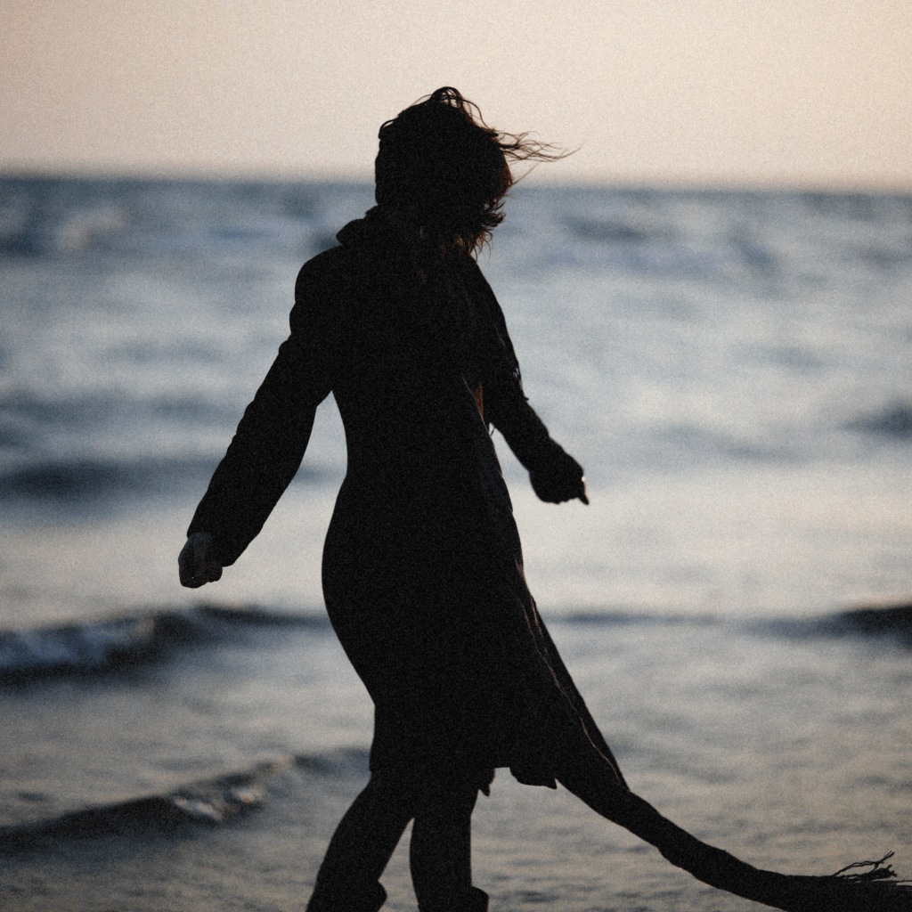 Silhouette of a Woman Walking on the Beach