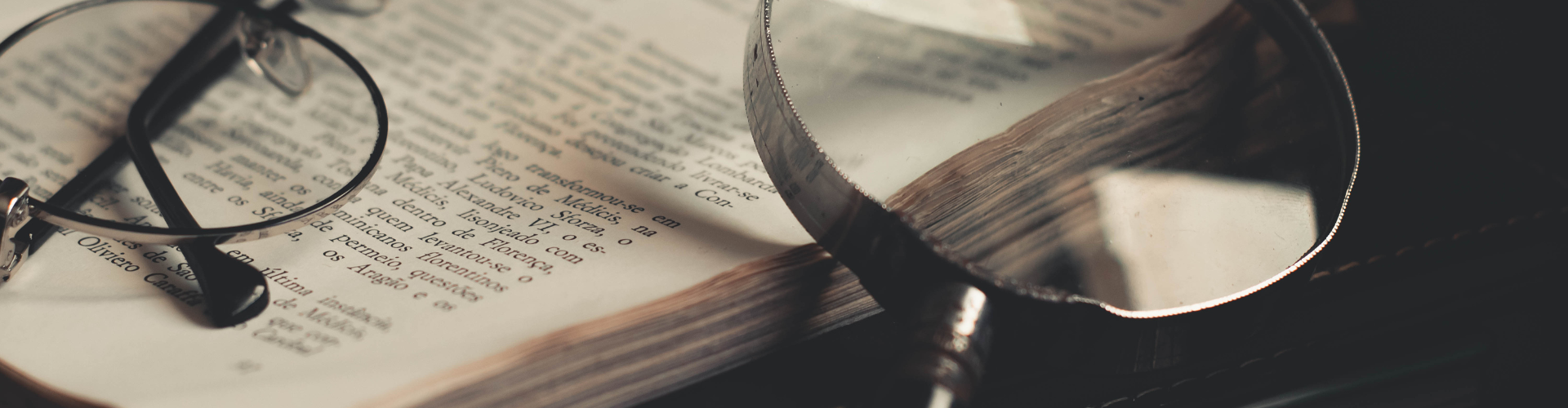 Gray Magnifying Glass and Eyeglasses on Top of Open Book